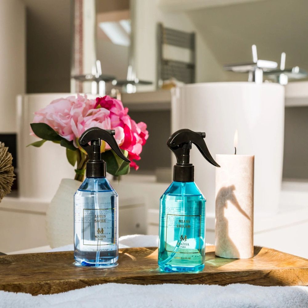 Zwei blaue Sprühflaschen mit schwarzem Sprühkopf. Aufschrift: Maison Maïssa. Auf einem Holzbrett, im Badezimmer.