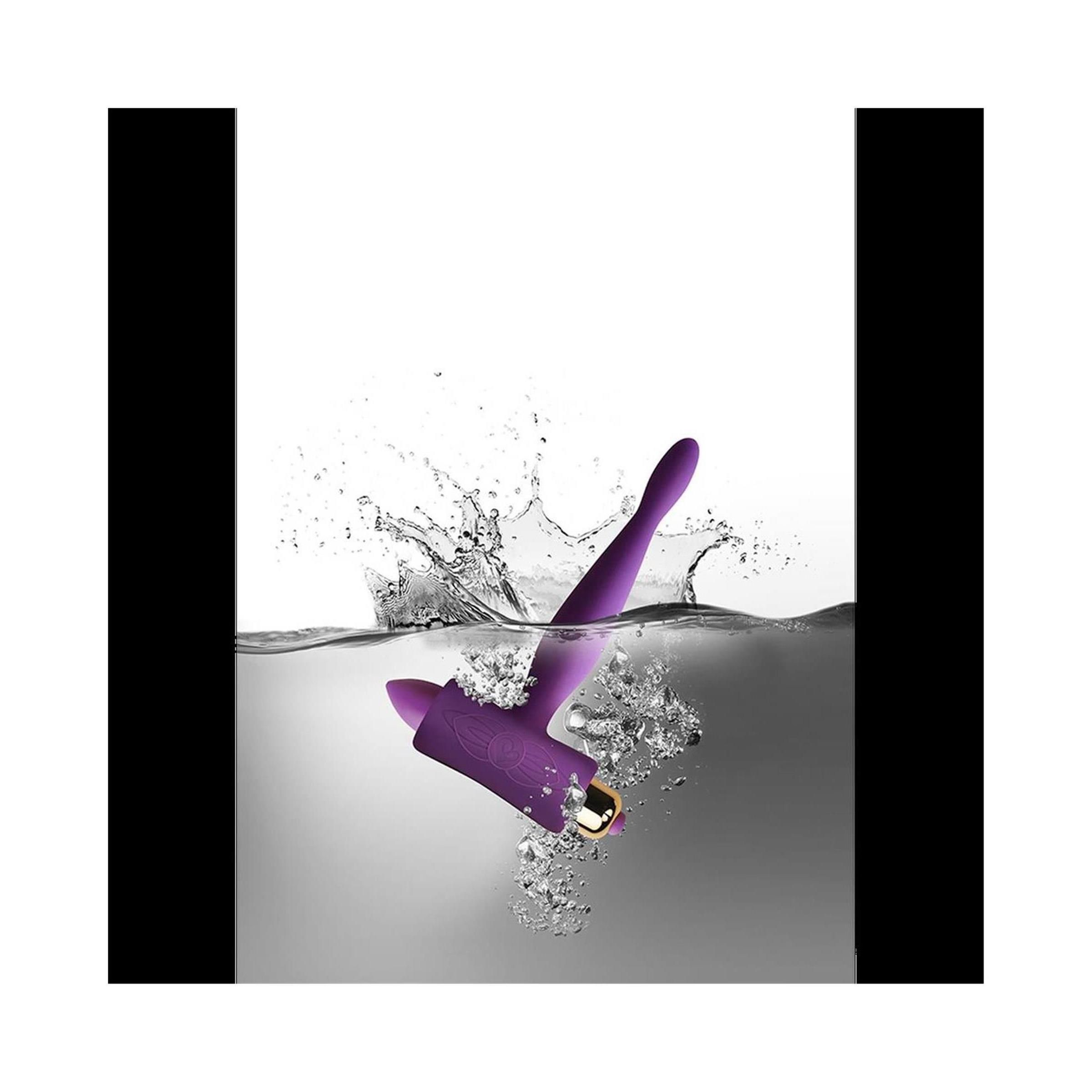 Lila Analspielzeug im Wasser. Spritzwasser umgibt das Produkt.