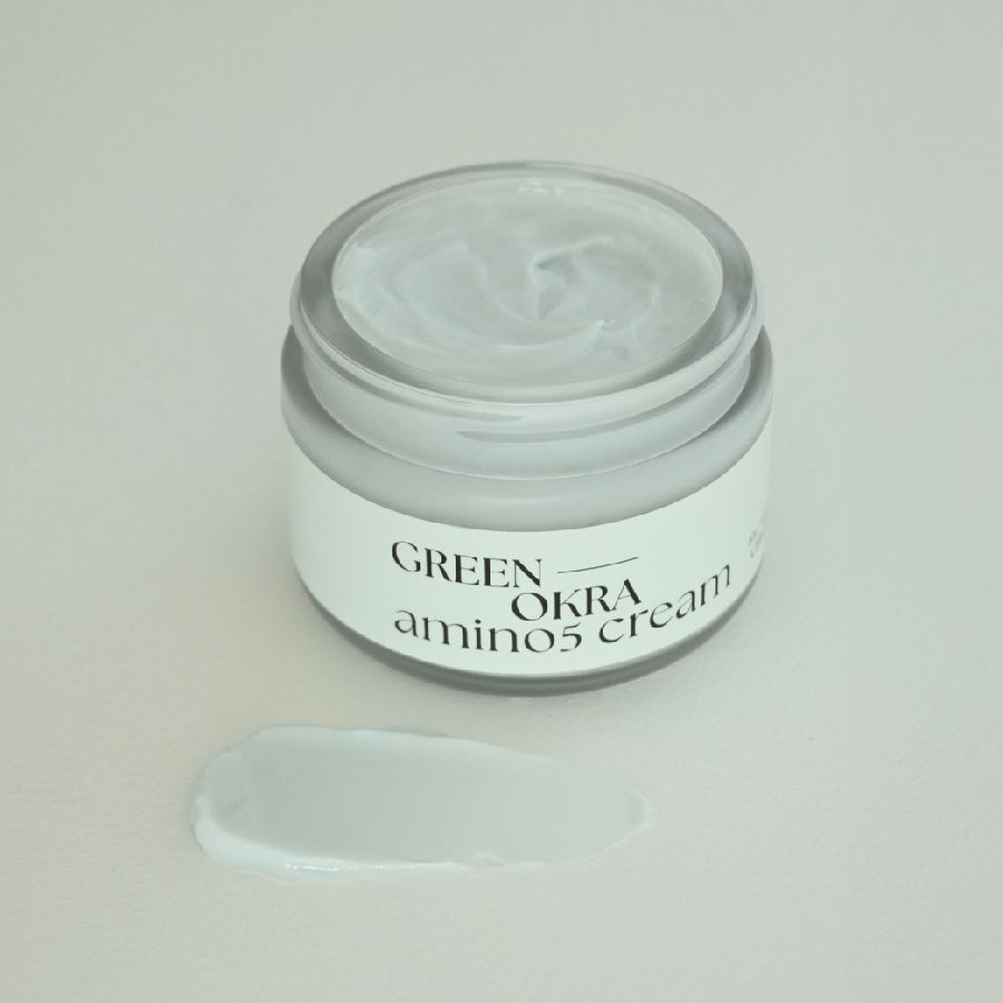 Creme-Glas mit weißem Etikett und Creme-Klecks daneben. Aufschrift: GREEN OKRA amino5 cream.