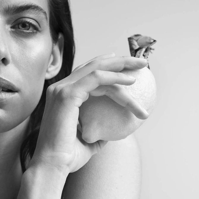 Schwarz-Weiß-Porträt einer Frau, die eine Zitrone hält. Die Frau blickt in die Kamera.