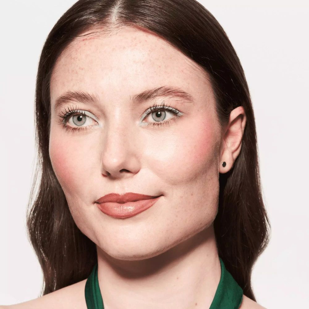 Porträt einer Frau mit hellgrünem Kajalstrich am Auge. Lippen und Wangen geschminkt.