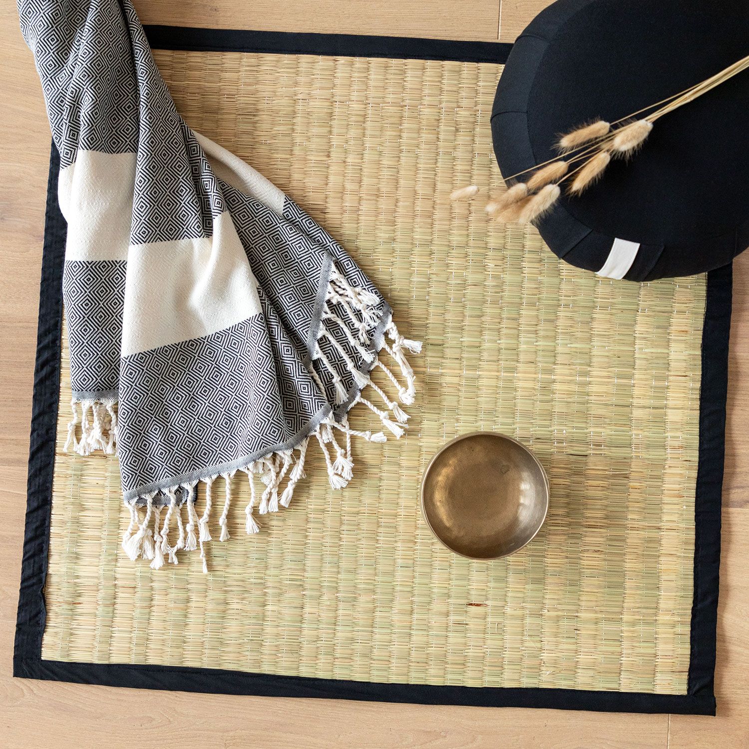 Tatami-Matte mit schwarzem Rand, darauf eine Decke, eine Schale und ein Kissen.