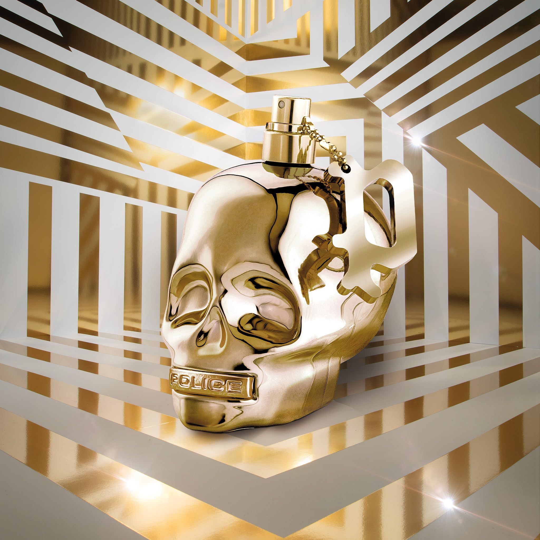 Goldener Totenkopf-Parfümflakon mit Anhänger, vor abstraktem Hintergrund.