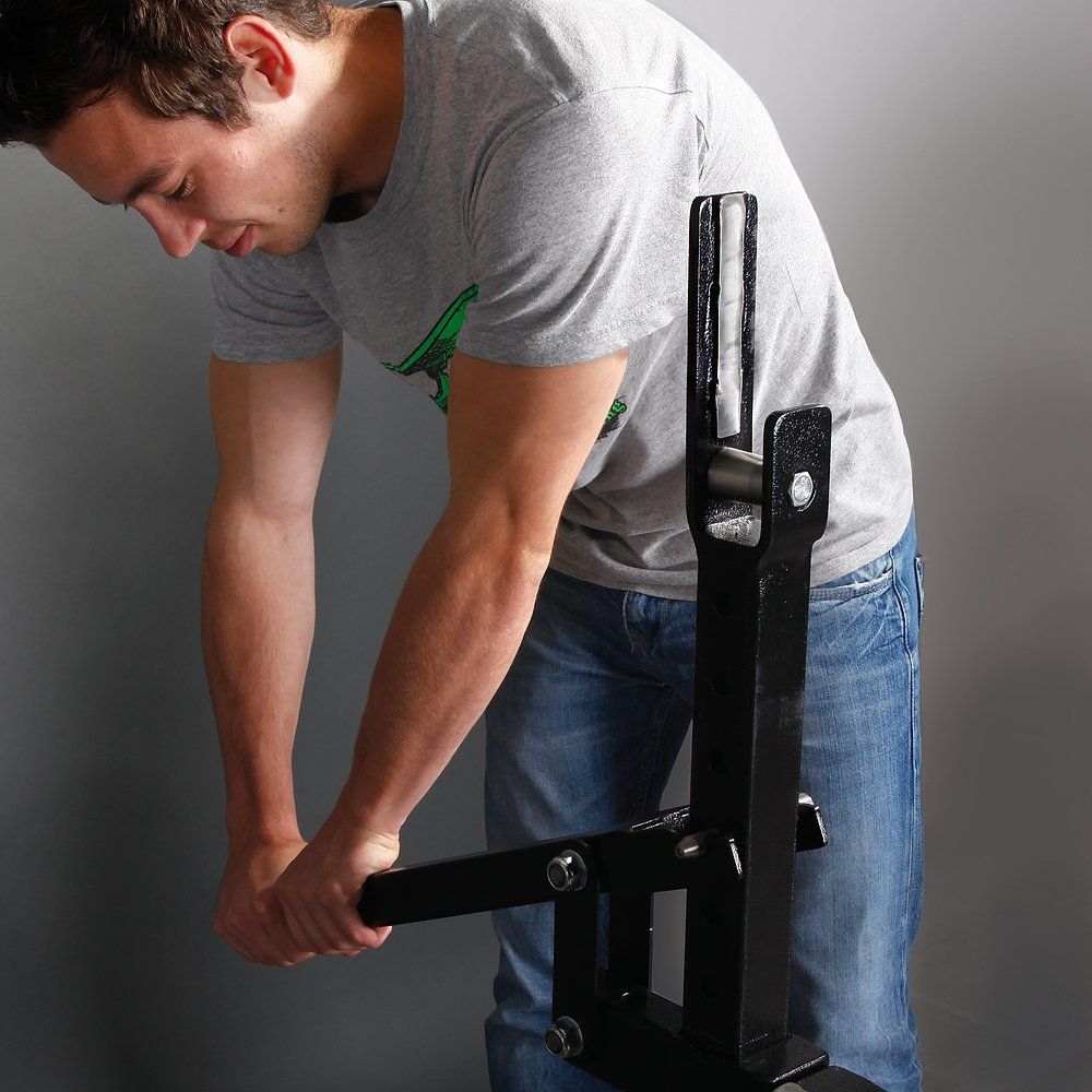 Schwarze Metallkonstruktion mit Mann. Der Mann hält ein schwarzes Metallteil fest. Grauer Hintergrund.