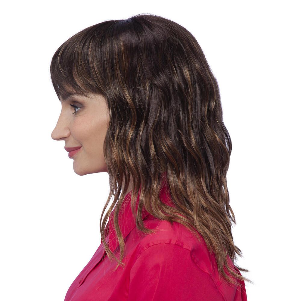 Perücke Kiky von trendhair. Braun mit Pony und gewelltem Haar. Frau trägt rotes Hemd. Profilansicht.