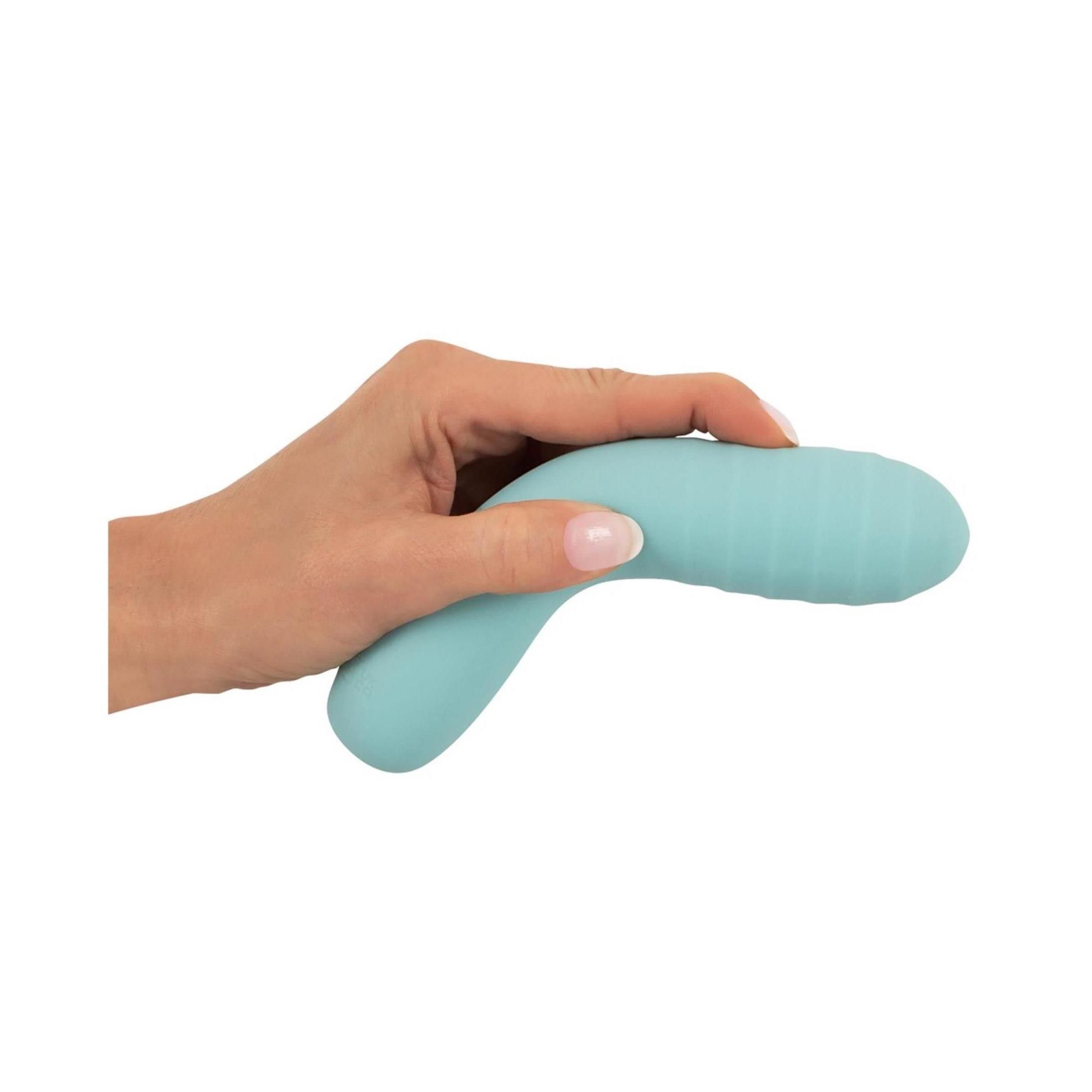Türkisfarbener Vibrator in einer Hand gehalten. Geriffelte Spitze, glatter Schaft.