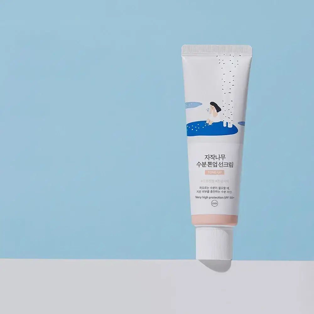 Sonnencreme-Tube. Weiß, mit rosa Spitze. Koreanischer Text. SPF 50+ PA++++. Auf blauem Hintergrund.
