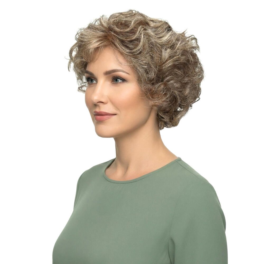 Perücke mit lockigem, blondiertem Haar. Die Frau trägt ein grünes Oberteil. Seitenansicht.