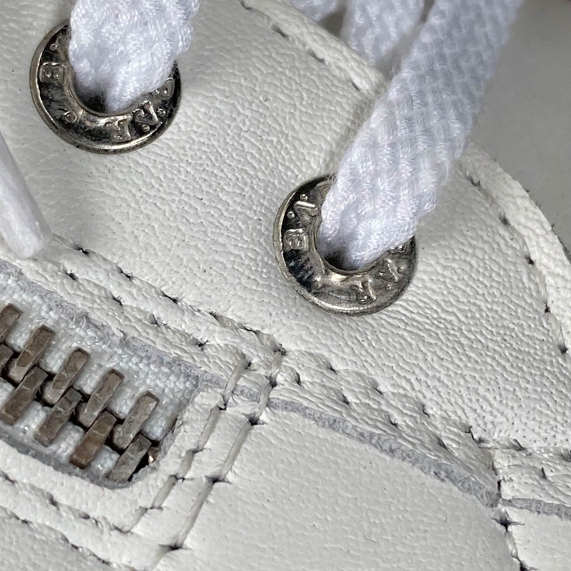Nahaufnahme von Metallösen an einem weißen Schuh. Runde Form mit Logo.