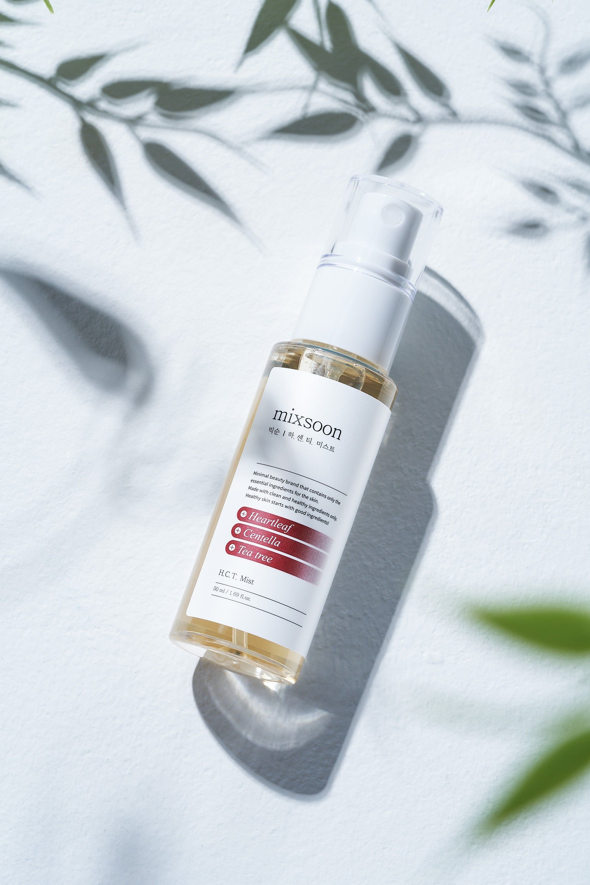 Eine "mixsoon H.C.T. Mist" Sprühflasche mit Schatten von Blättern. Transparente Flasche mit weißem Sprühkopf.