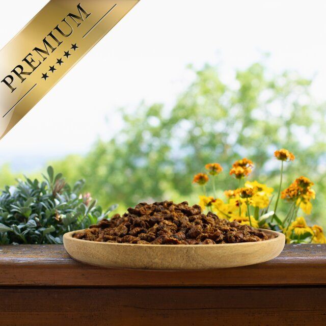 Getrocknete Seidenraupen in einer Holzschale. Premium-Banner im Eck. Hintergrund: Fenster mit Blumen und Bäumen.