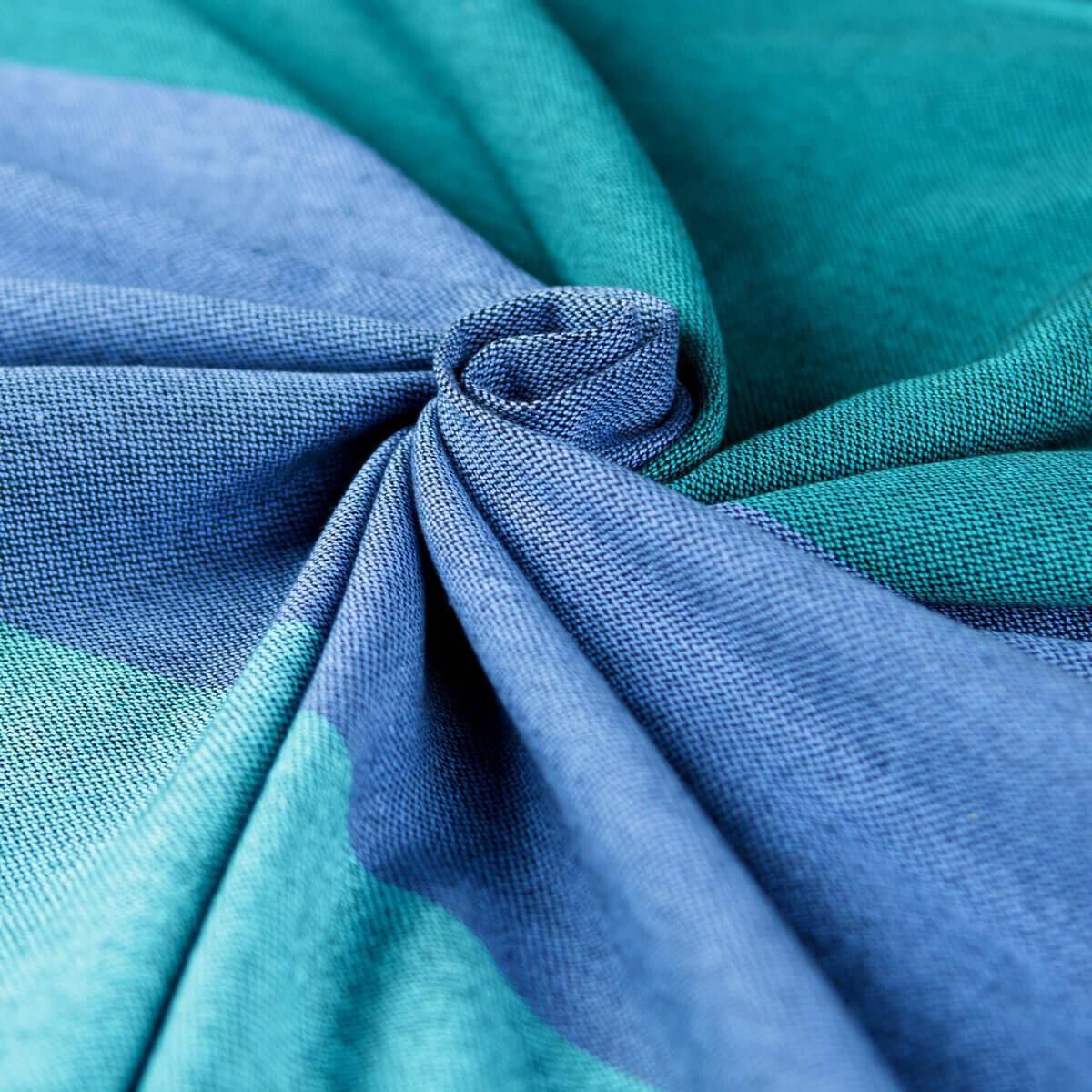 Nahaufnahme einer Stoffoberfläche in Blau- und Grüntönen. Stoff ist gefaltet und verdreht.