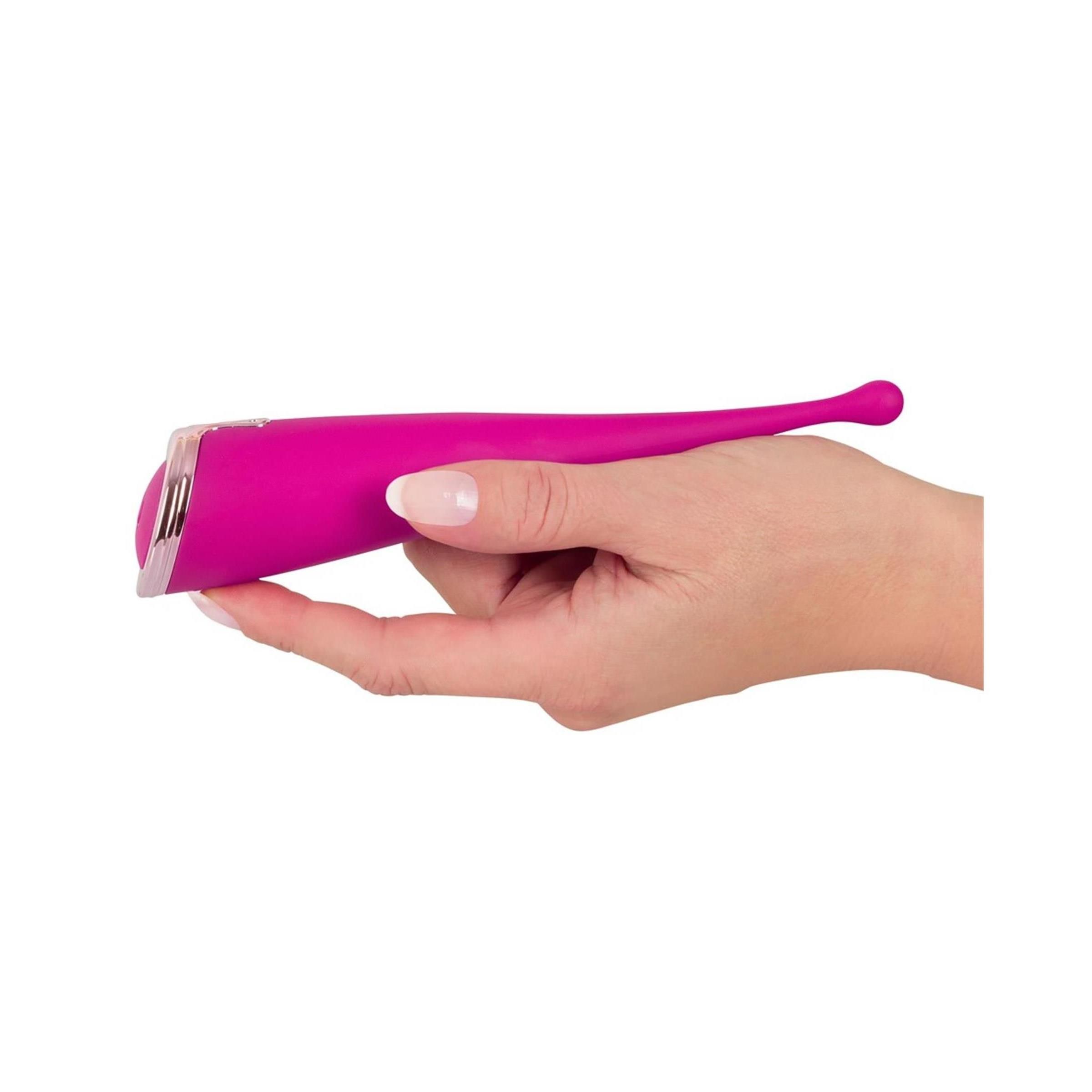 Hand hält rosa Vibrator. Konische Form mit abgerundeter Spitze. Silberfarbener Ring am unteren Ende.