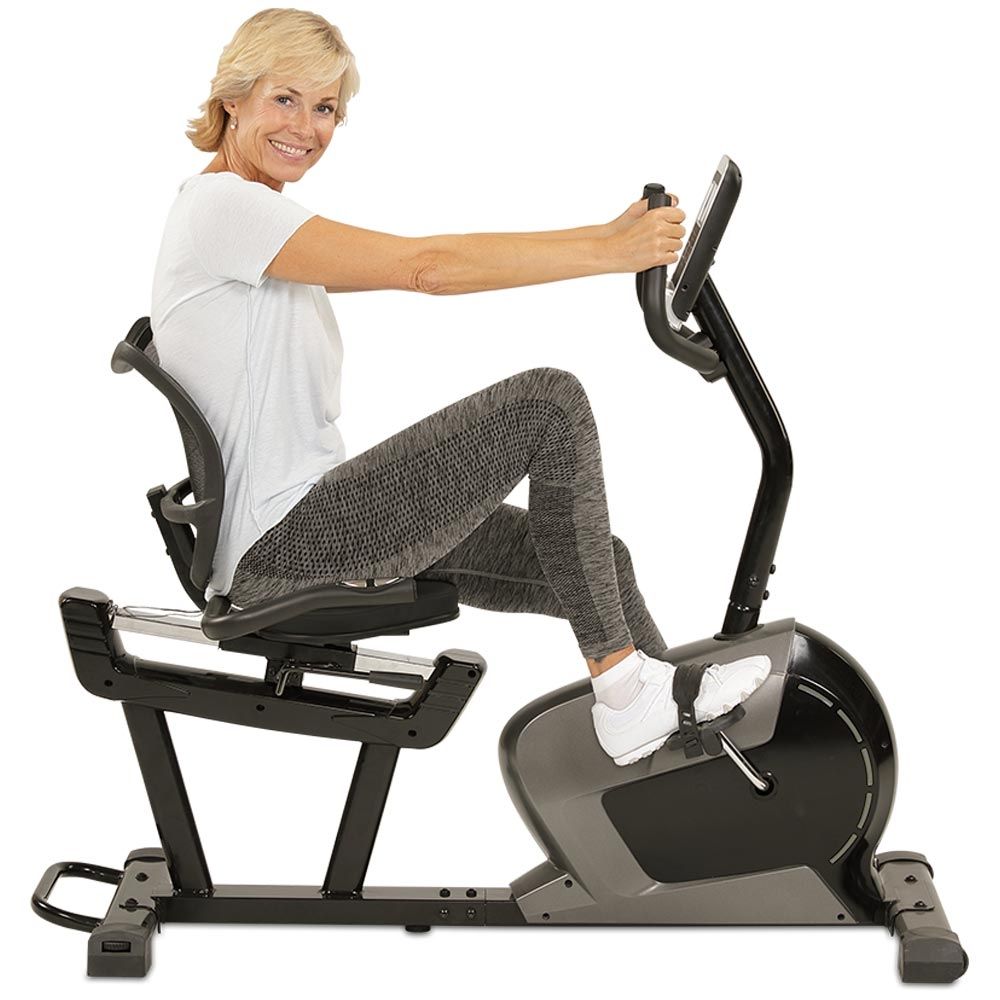 Frau sitzt auf einem Ergometer. Sie trägt Sportkleidung. Das Gerät hat ein Display.