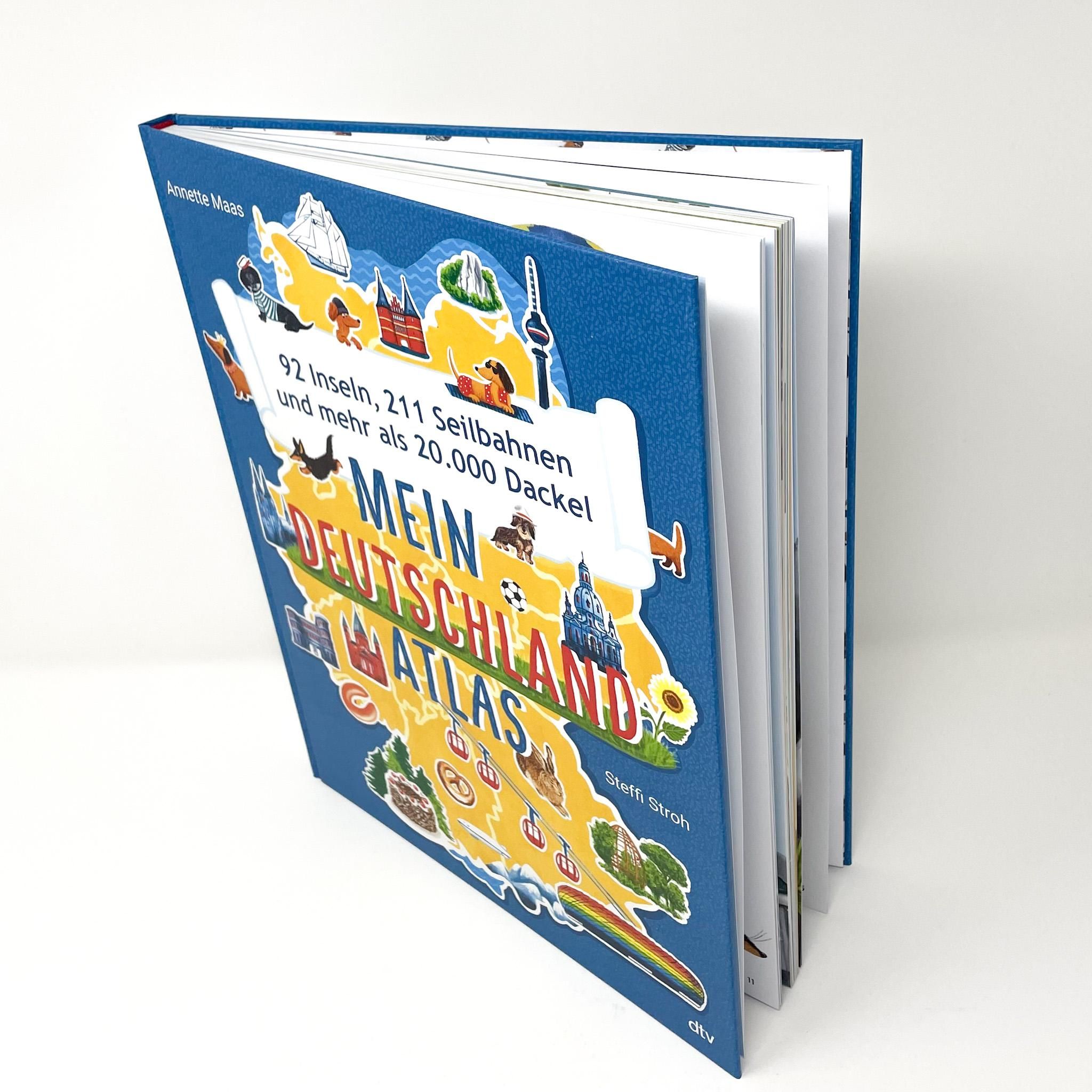 Buch: Mein Deutschlandatlas. Geöffnet, blaue Einband, Titel mit Illustrationen von Deutschland, Dackeln, Seilbahnen. Verlag: dtv.
