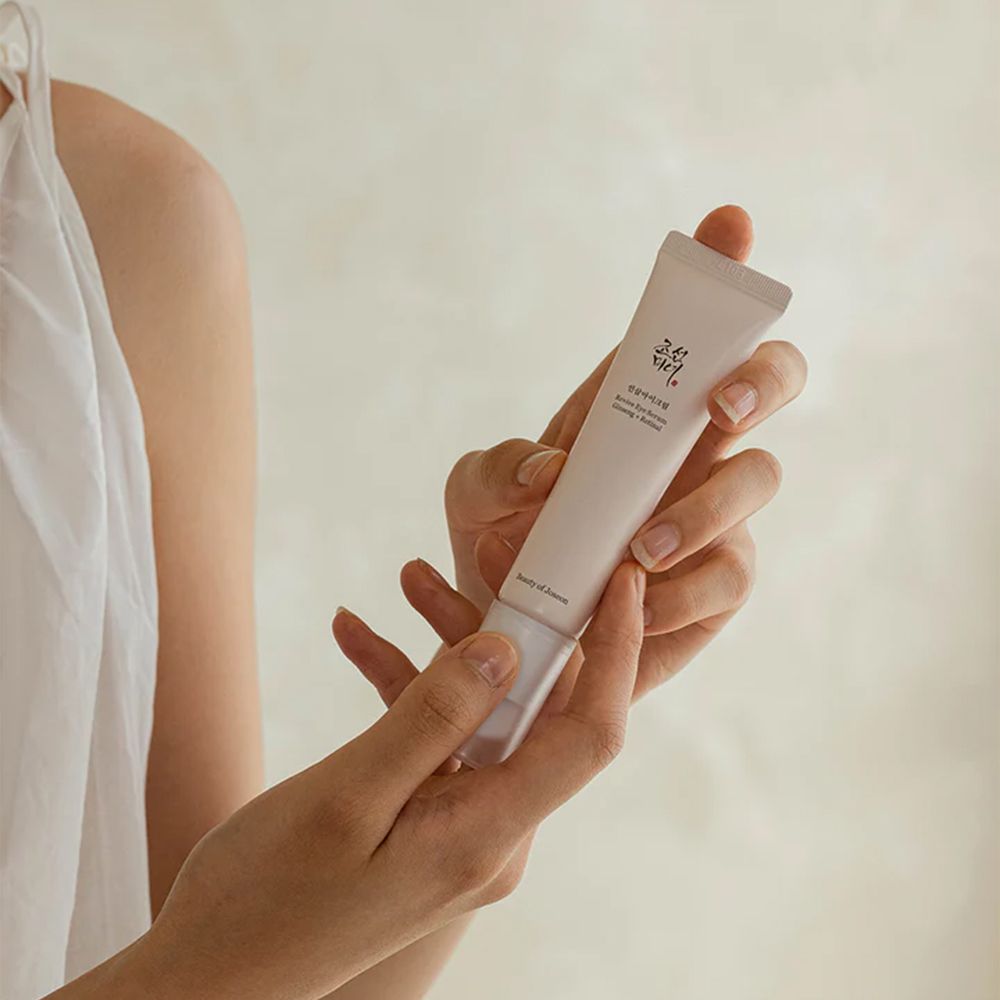 Hände halten eine Beauty of Joseon Augencreme Tube.
