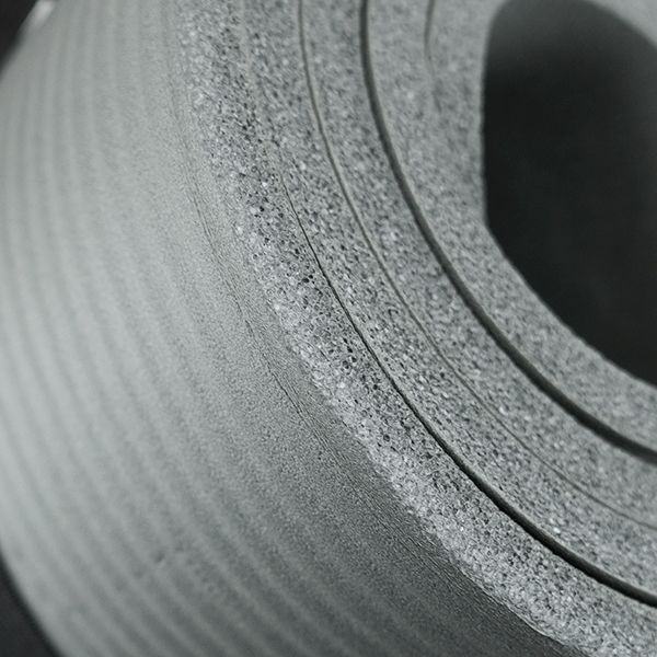 Gerollte graue Fitnessmatte, Nahaufnahme. Die Matte besteht aus mehreren Schichten.