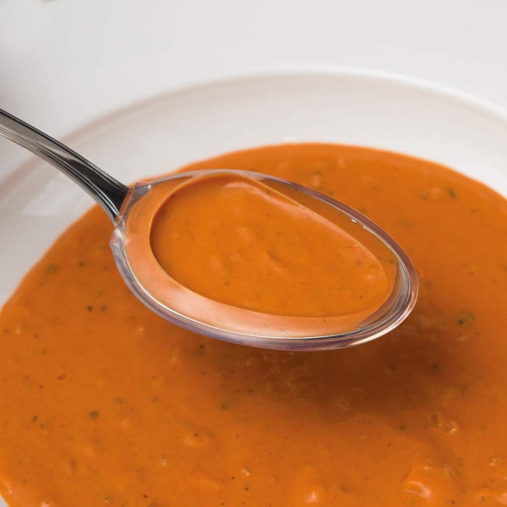 Transparenter Löffelaufsatz in Suppe. Oval, mit Griff. Teilweise gefüllt.