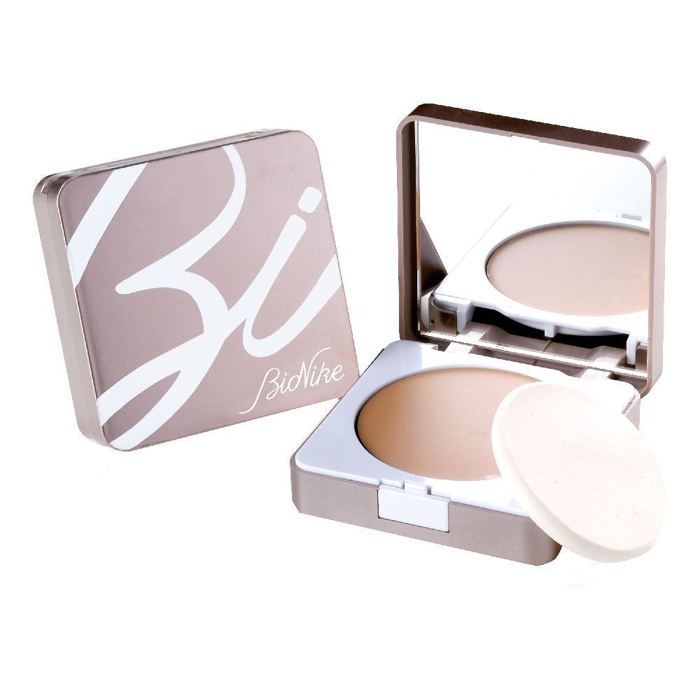 Fondotinta compatto aperto, specchio, spugnetta. Astuccio beige con logo bianco. Polvere beige visibile.