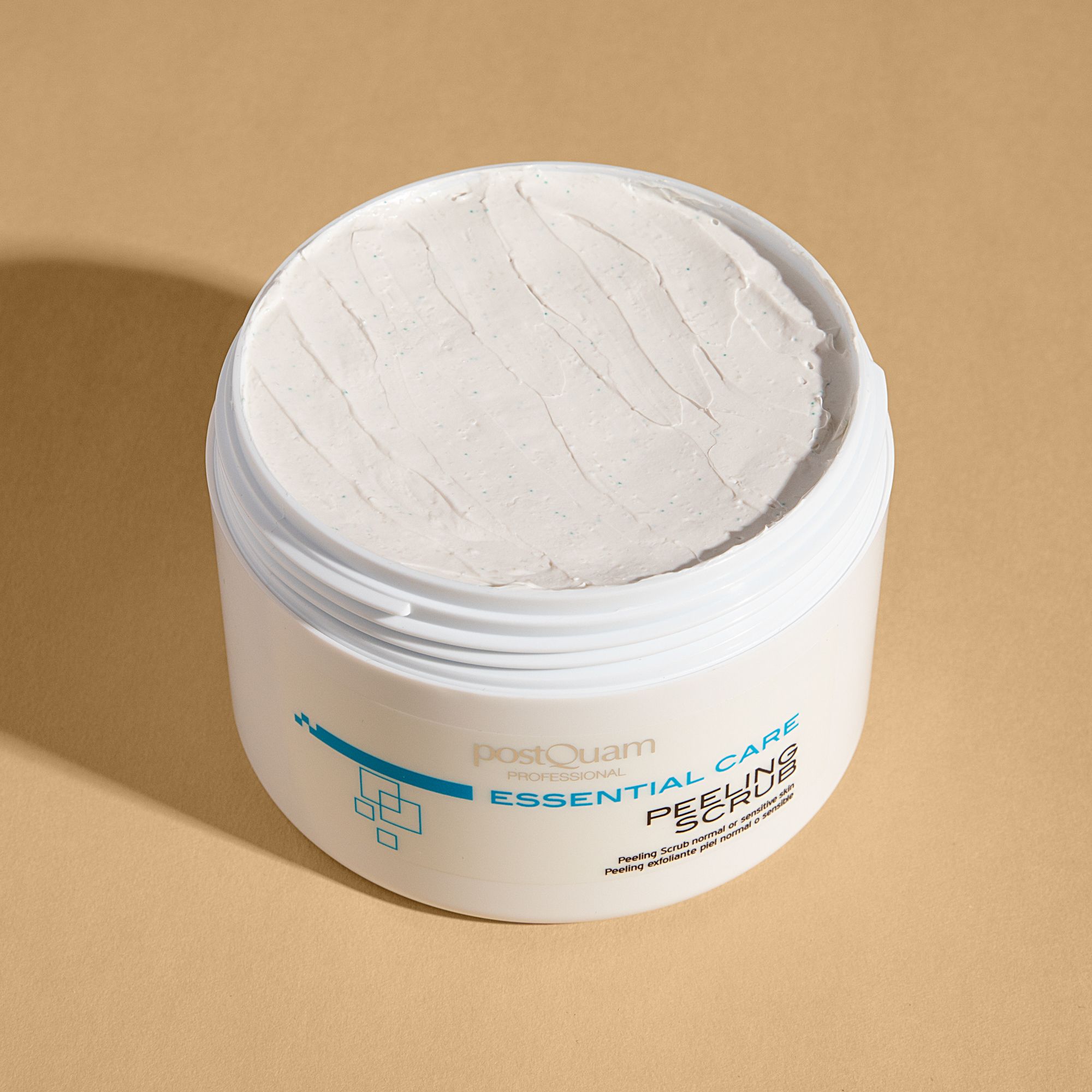Weißer Tiegel, geöffnet, mit cremiger Substanz. Aufschrift: Essential Care Peeling Scrub. Für normale oder sensible Haut.