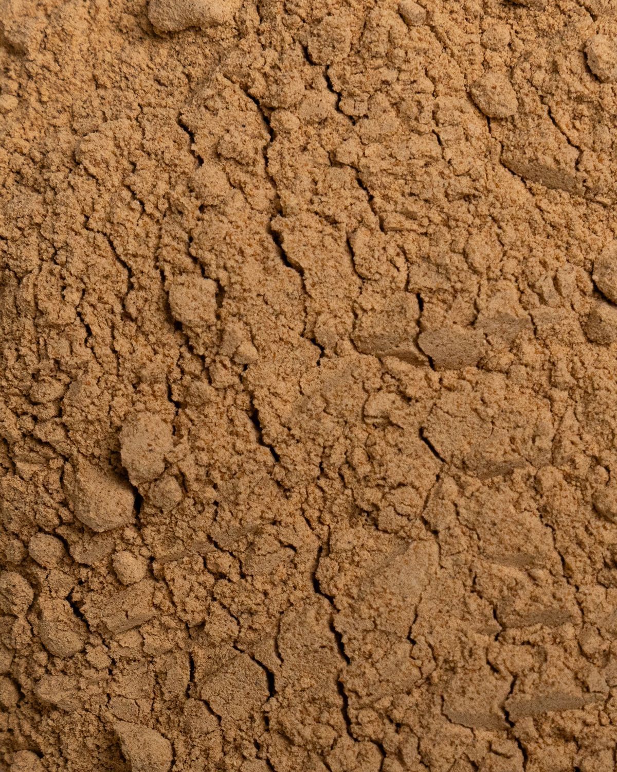 Nahaufnahme von braunem Maca-Pulver. Die Textur ist deutlich sichtbar.