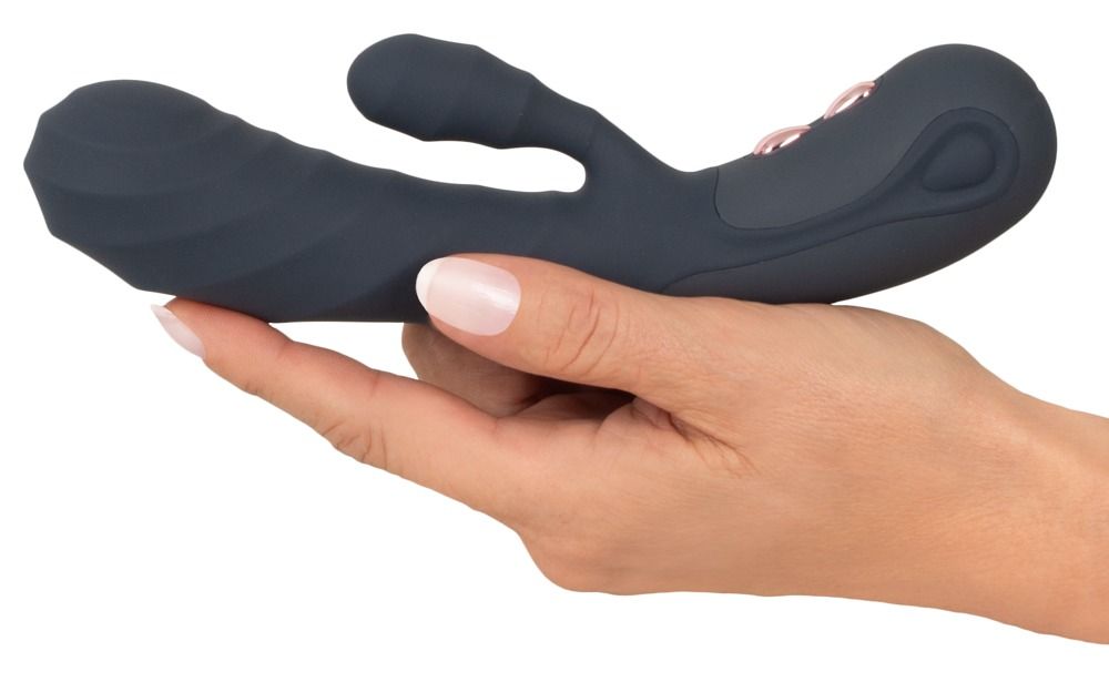 Dunkelgrauer Vibrator mit zwei Stimulationsbereichen, gehalten in einer Hand. Aus Silikon.