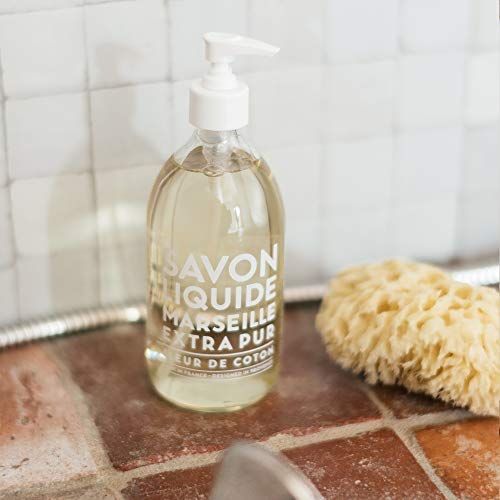 Transparente Flasche mit weißem Pumpkopf, neben einem Schwamm. Aufschrift: Savon Liquide Marseille Extra Pur Fleur de Coton.