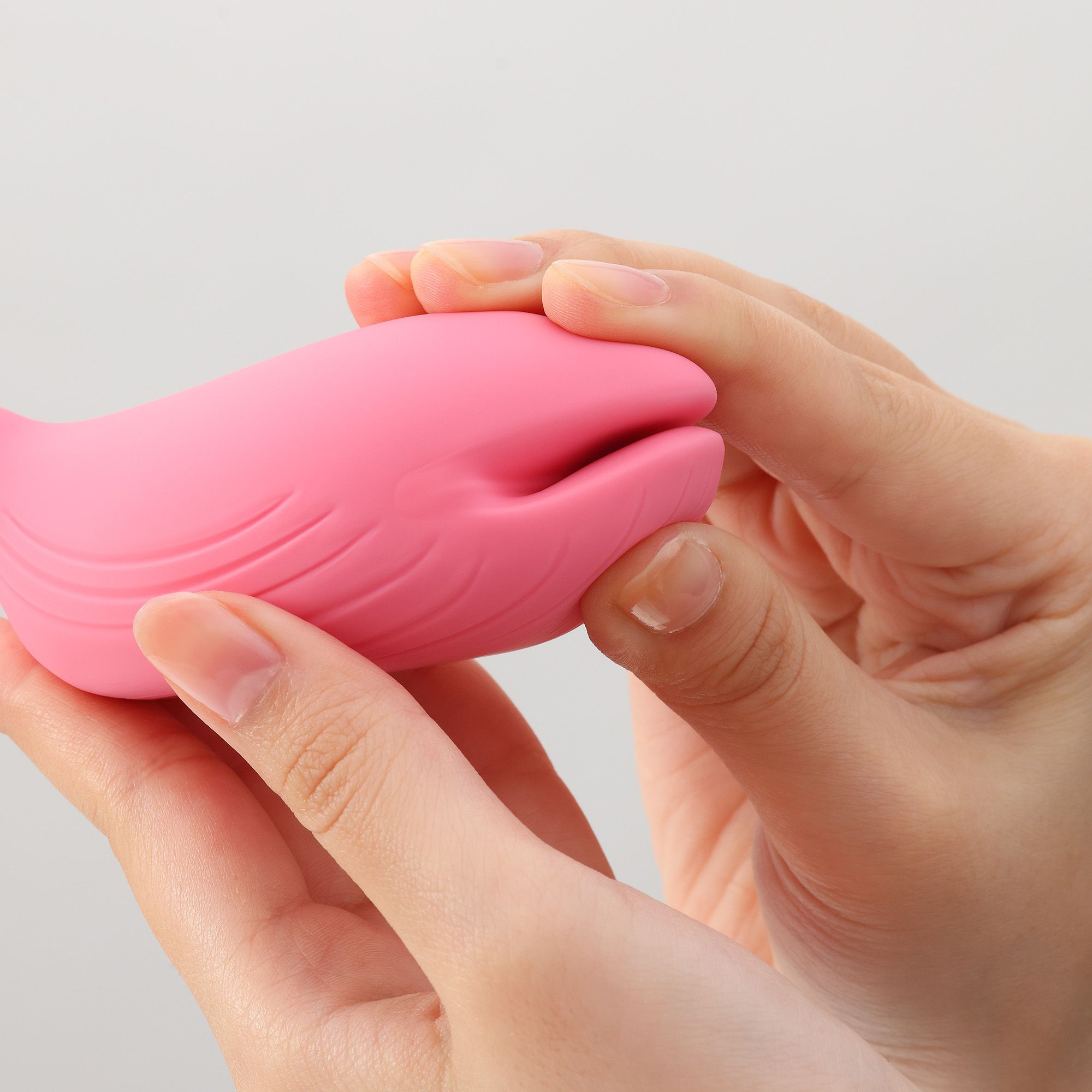 Hände halten rosa Vibrator. Organische Form mit geriffelter Oberfläche und Öffnung. Nahaufnahme.