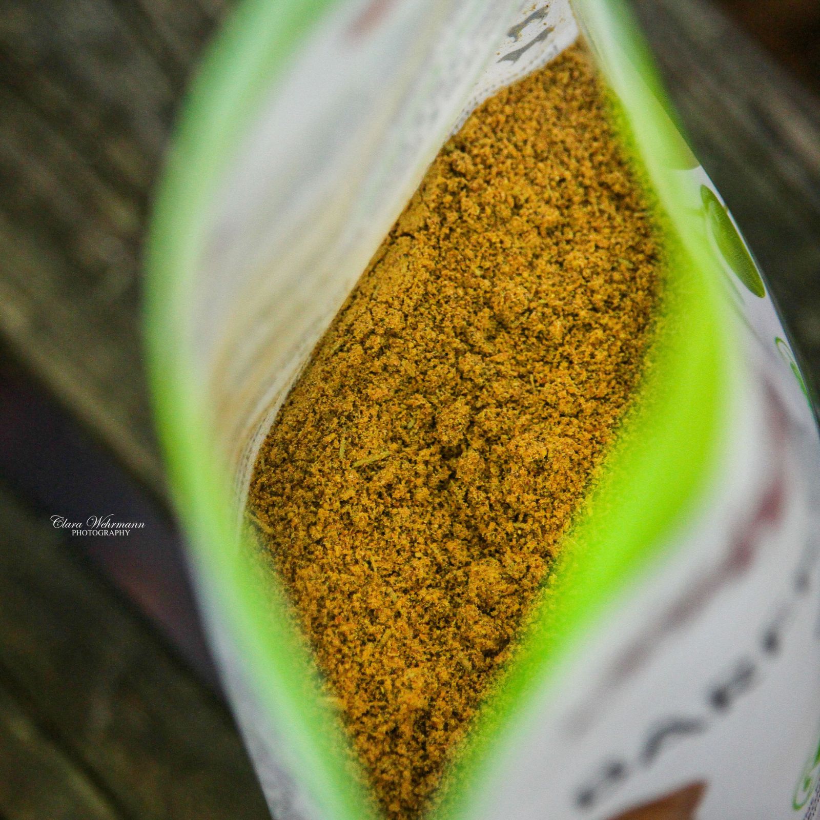 Geöffnete Verpackung von Stiefel Barf-Kräuter. Gelb-braunes Kräuterpulver im Inneren, grüne Verpackung mit Logo sichtbar.