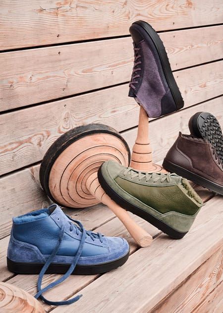Mehrere Stiefeletten auf Holzuntergrund. Grün, blau, braun und lila. Verschiedene Perspektiven.