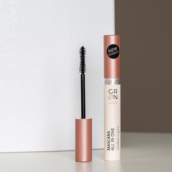 Mascara-Tube und Bürste. Tube: hell, Schriftzug GRN, Mascara All in One, zertifiziert organic. Aufkleber: New Formula. Bürste: schwarz.