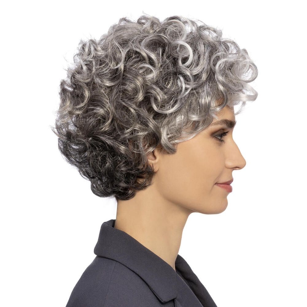 Perücke mit lockigem, grauem Haar. Die Frau trägt einen dunklen Blazer. Seitenansicht.
