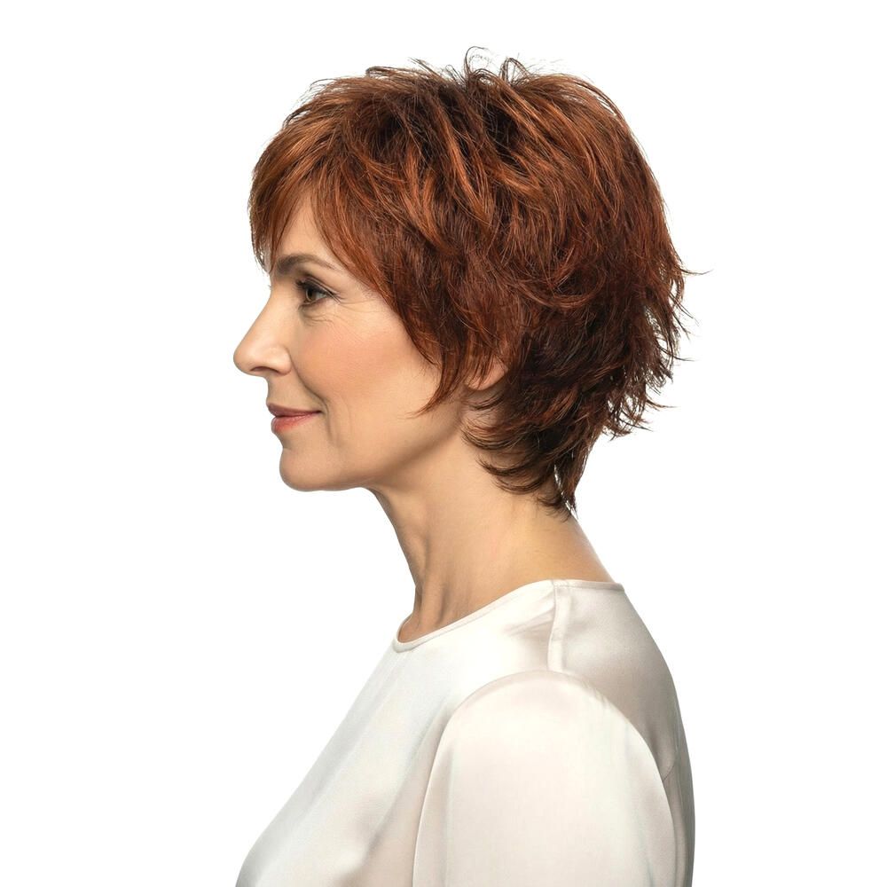 Profil einer Frau mit rotbrauner Perücke. Kurze, gewellte Haare. Helle Haut, weißes Oberteil. Blick nach vorne.
