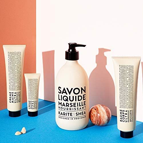 Produktreihe: Flasche Savon Liquide Marseille Nourrissant Karité Shea, Cremes und eine Kugel. Blau-roter Hintergrund.