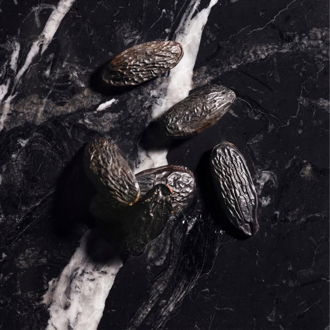 Bohnen auf schwarzem Marmor. Dunkle, längliche Form. Hintergrund: Marmor.