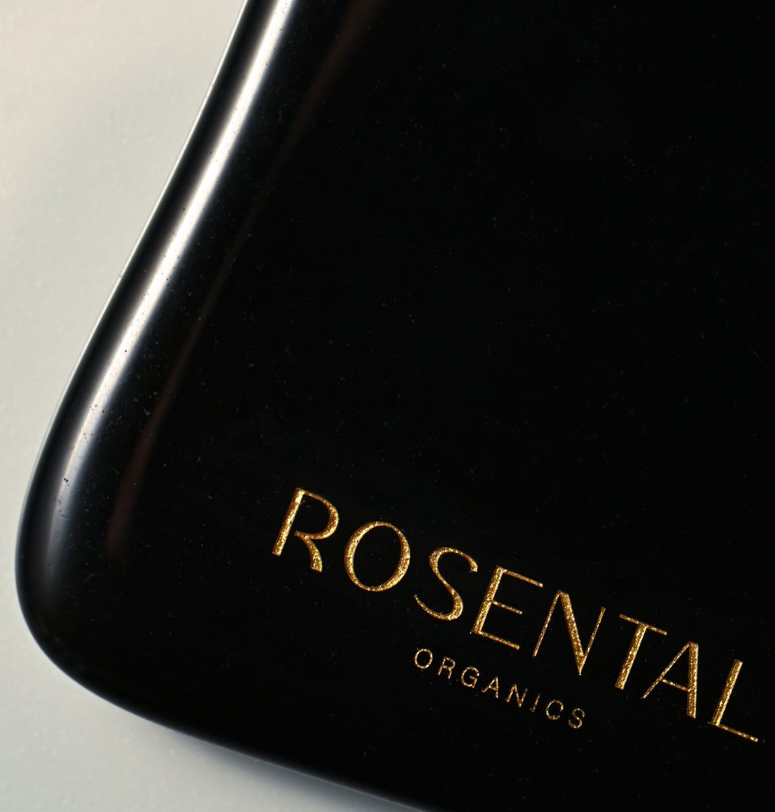 Nahaufnahme eines schwarzen Gua Sha. Goldener Schriftzug: ROSENTAL ORGANICS. U-Form mit abgerundeten Kanten.