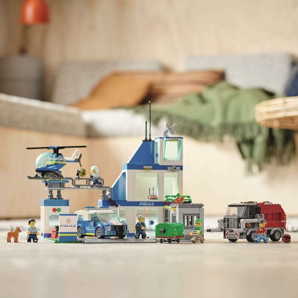 LEGO City Police 60316. Il set mostra una stazione di polizia blu con un elicottero, un'auto della polizia e un camion della spazzatura. La scena è costruita su un pavimento. Sono presenti anche personaggi e accessori.