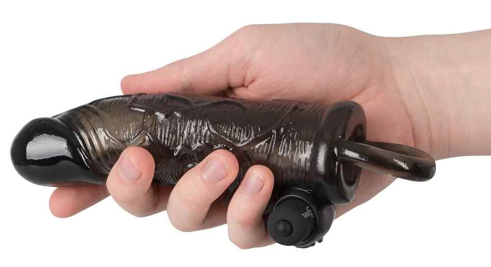 Schwarzes Verlängerungsstück in einer Hand gehalten. Ring und Aufsatz sichtbar. Geformte Oberfläche.