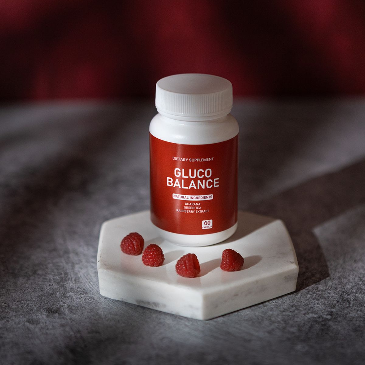 Eine weiße Flasche mit rotem Etikett und Himbeeren auf einer weißen Platte. Auf dem Etikett steht "GLUCO BALANCE".