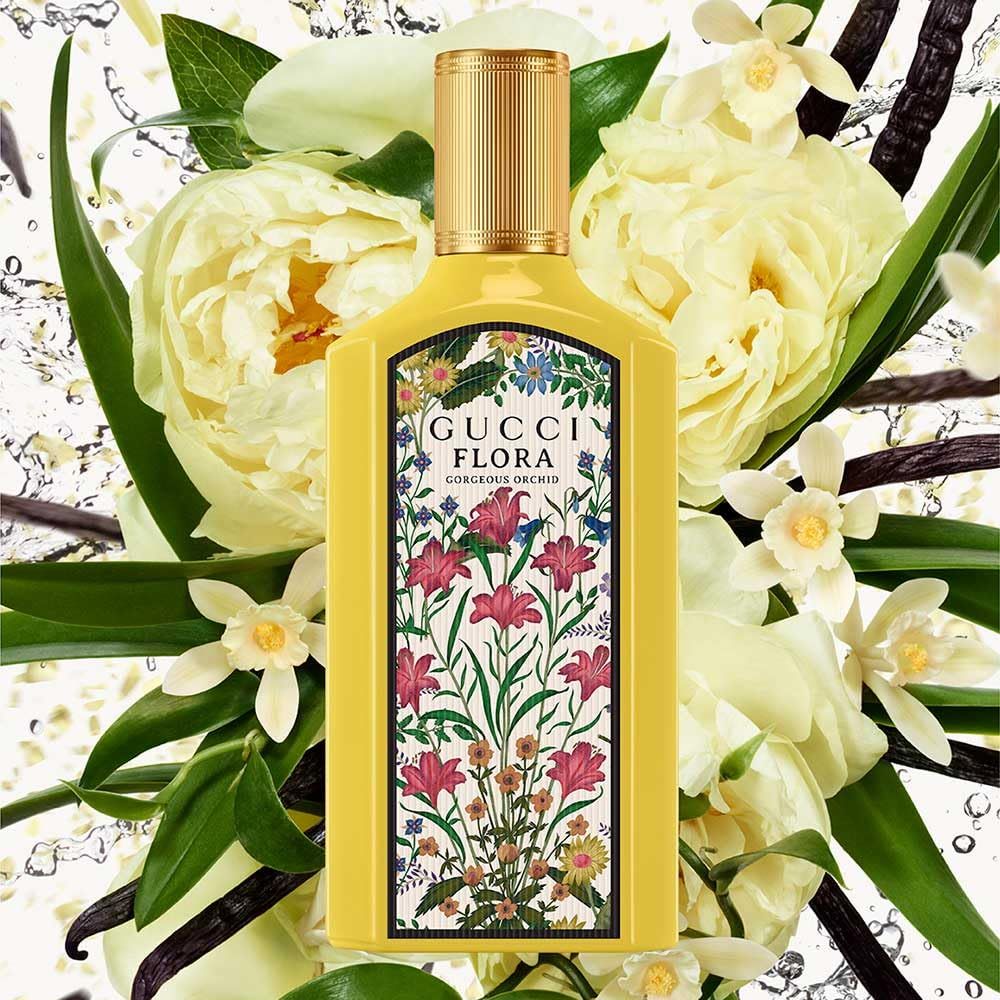 Gelbe Flasche mit floralem Muster, umgeben von Blumen. Aufschrift: Gucci Flora Gorgeous Orchid.
