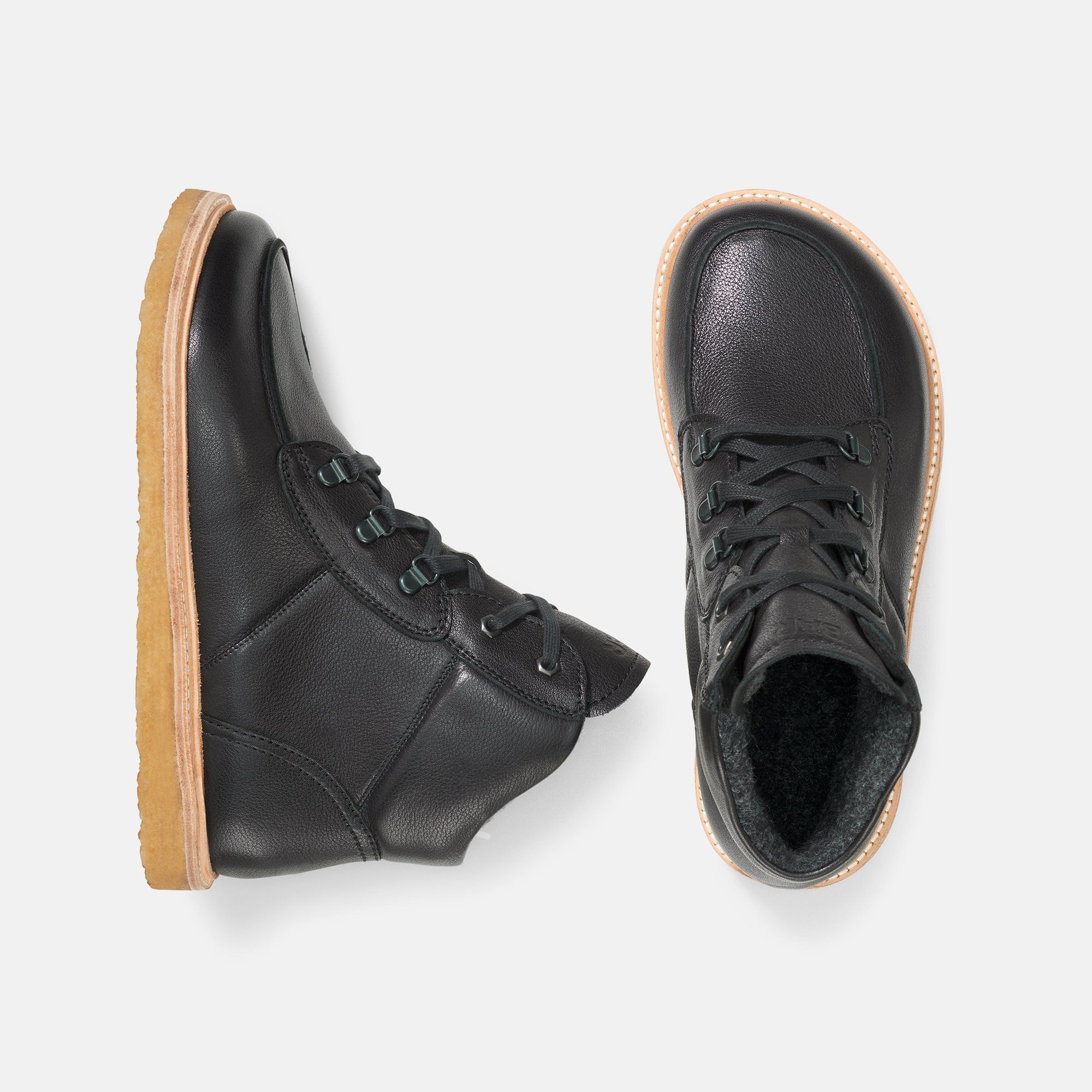 Zwei schwarze Lederstiefeletten mit heller Sohle. Draufsicht, Innenfutter sichtbar.