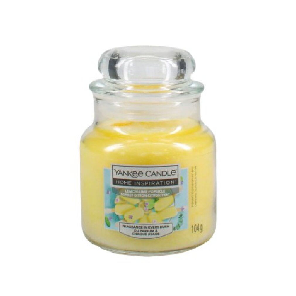 Gelbe Duftkerze im Glas mit Deckel. Aufkleber mit Produktnamen und Logo. Aufschrift: Lemon Lime Popsicle. Gewicht: 104g.
