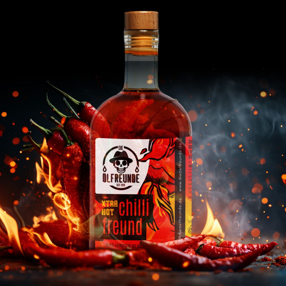 Glasflasche mit roter Flüssigkeit, Holzverschluss und Etikett. Text: Xtra Hot Chilli Freund. Flammen und Chilischoten im Hintergrund.