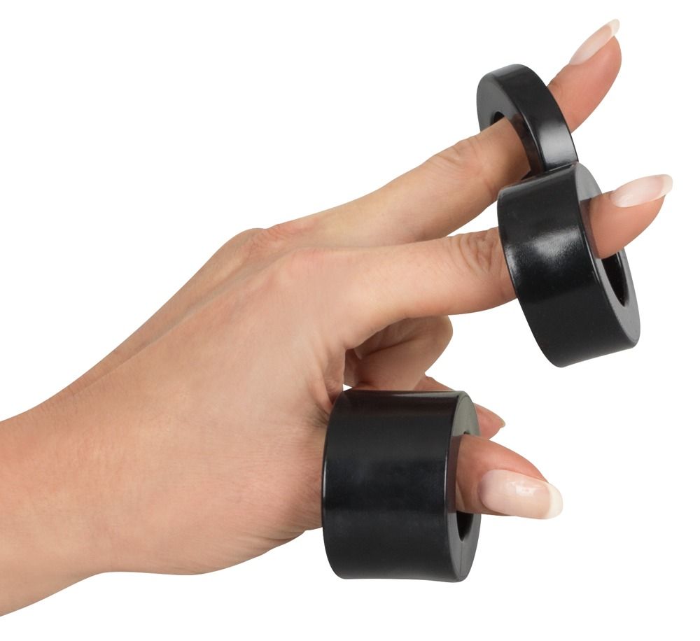 Hand mit drei schwarzen Ringen auf den Fingern. Ringe sind zylindrisch.