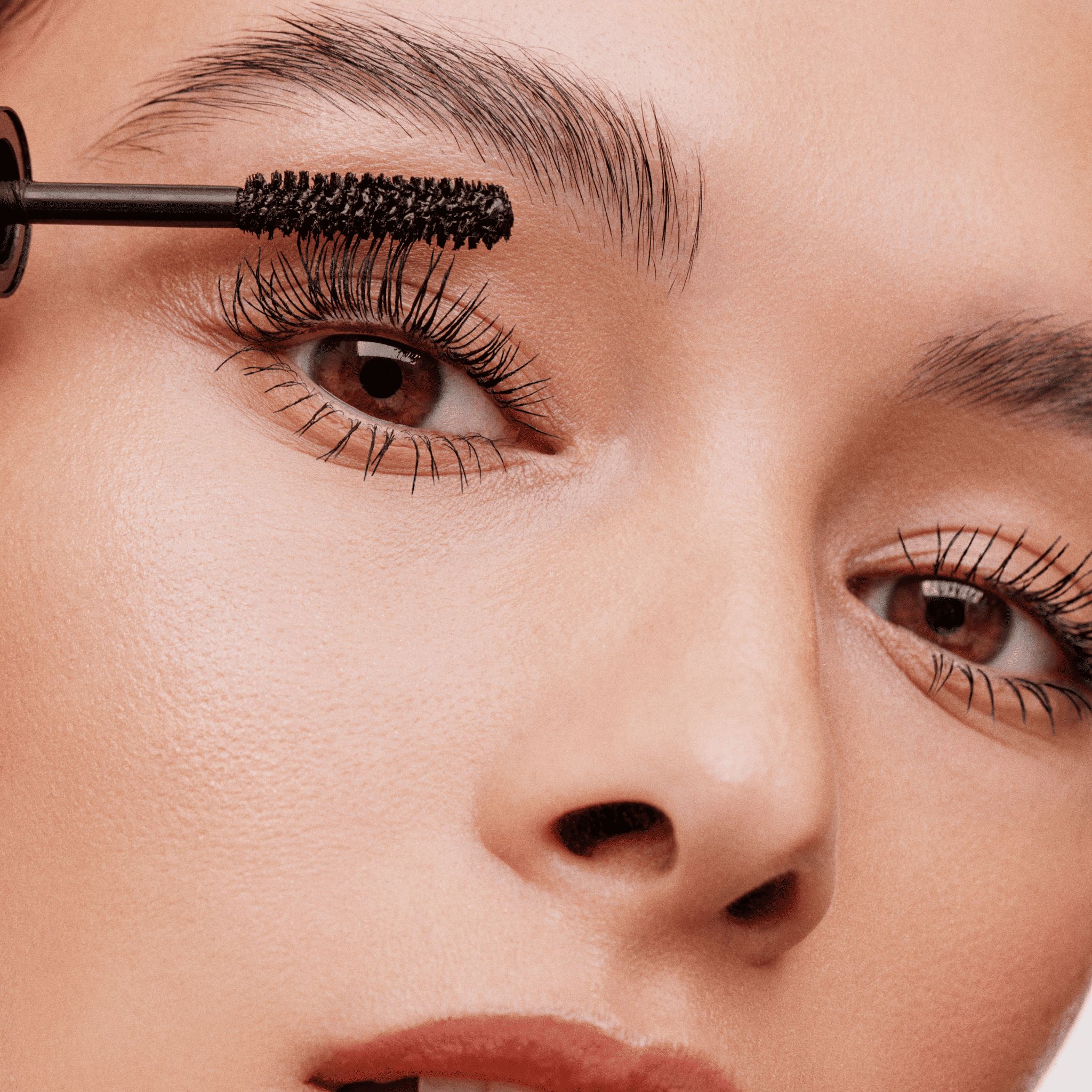 Frau trägt schwarzen Mascara mit der schwarzen Bürste des Double-Ended Volume Sets auf.
