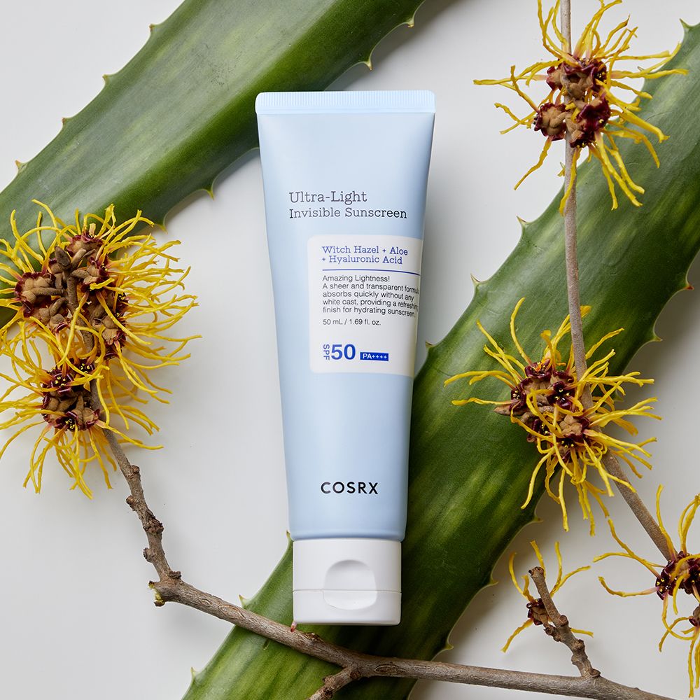 COSRX Ultra Light Invisible Sunscreen Tube, umgeben von Aloe und Witch Hazel.