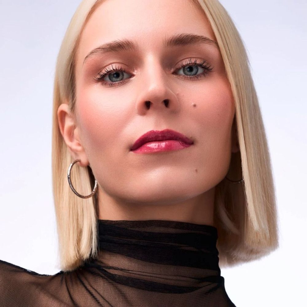 Frau mit blondem Haar, blauen Augen und rotem Lippenstift.
