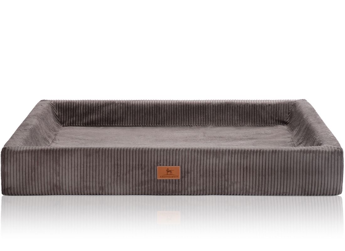Orthopädisches Hundebett, rechteckig, grau, Cord-Optik. Mit erhöhtem Rand und Markenlogo. Auf weißem Hintergrund.