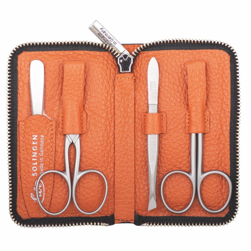 Orange Lederetui mit Reißverschluss, geöffnet, mit 4 Maniküre-Instrumenten aus Edelstahl.