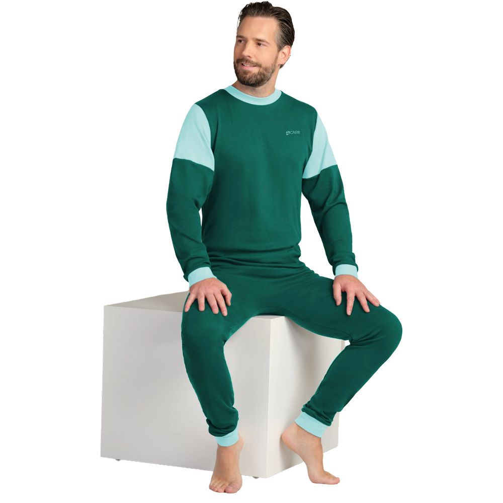 Grüner Overall mit hellblauen Akzenten an Ärmeln und Kragen. Mann sitzt auf weißem Würfel. Langärmlig, mit Füßen.